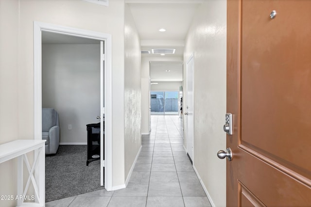 hallway with light tile patterned flooring, baseboards, visible vents, and light carpet