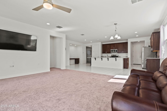 living area featuring recessed lighting, visible vents, light carpet, baseboards, and ceiling fan with notable chandelier