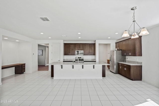 kitchen featuring stainless steel appliances, visible vents, hanging light fixtures, dark brown cabinets, and a kitchen bar