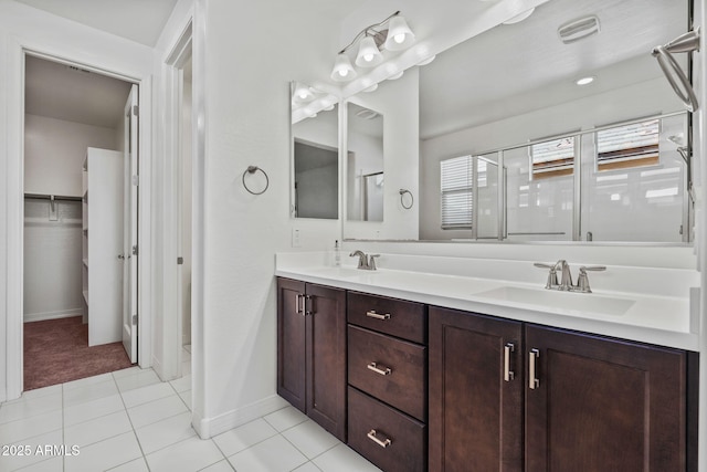 full bathroom featuring double vanity, tile patterned flooring, a walk in closet, and a sink