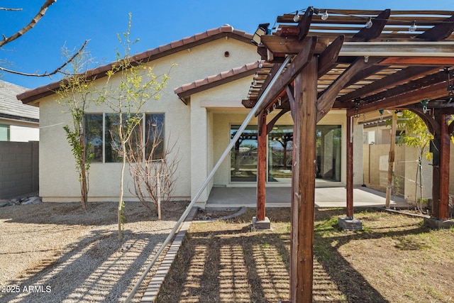 rear view of property featuring a patio, a tile roof, fence, and stucco siding