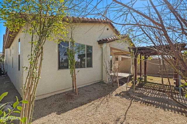 exterior space with a tile roof, stucco siding, fence, a pergola, and cooling unit