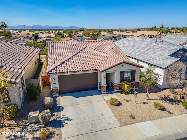 view of front facade with an attached garage, a mountain view, a tile roof, driveway, and stucco siding