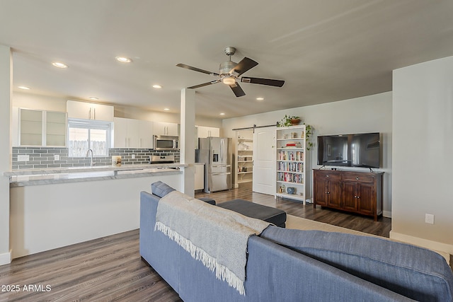 living area with recessed lighting, ceiling fan, dark wood-style floors, and a barn door