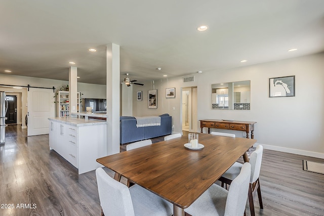 dining room featuring visible vents, dark wood-style flooring, baseboards, recessed lighting, and a barn door