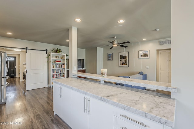kitchen with white cabinets, ceiling fan, a barn door, recessed lighting, and visible vents