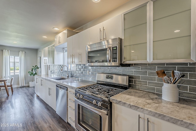 kitchen with backsplash, appliances with stainless steel finishes, dark wood-style floors, and a sink