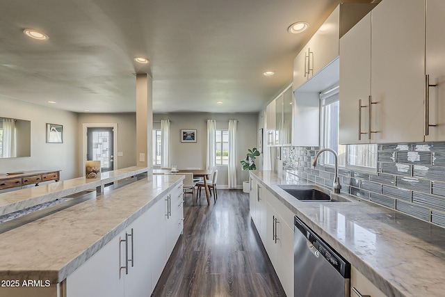 kitchen featuring tasteful backsplash, dishwasher, a sink, light stone counters, and dark wood-type flooring