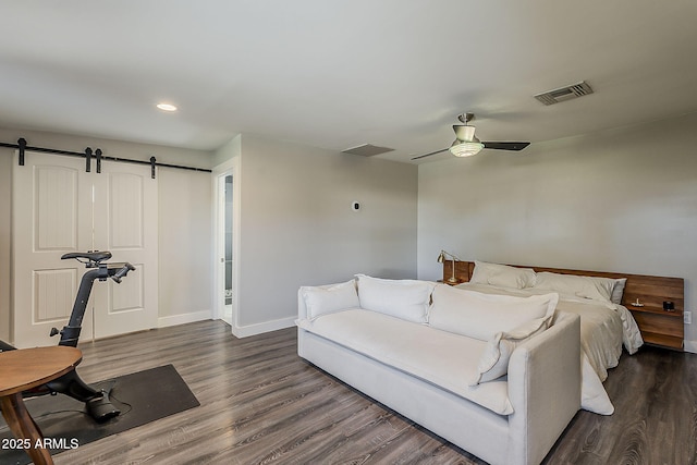 bedroom featuring visible vents, a barn door, baseboards, and dark wood-type flooring