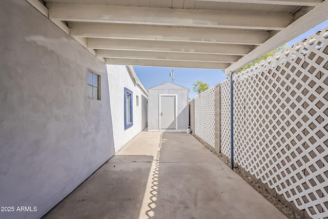 view of patio with an outbuilding, fence, and a storage shed