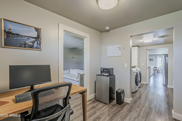 office area with baseboards, visible vents, independent washer and dryer, and wood finished floors