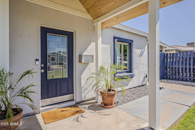 doorway to property with stucco siding and fence