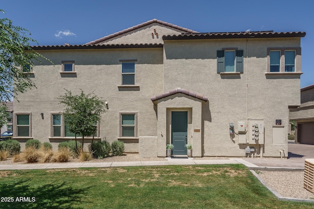 view of front facade featuring stucco siding, a front lawn, and a tiled roof