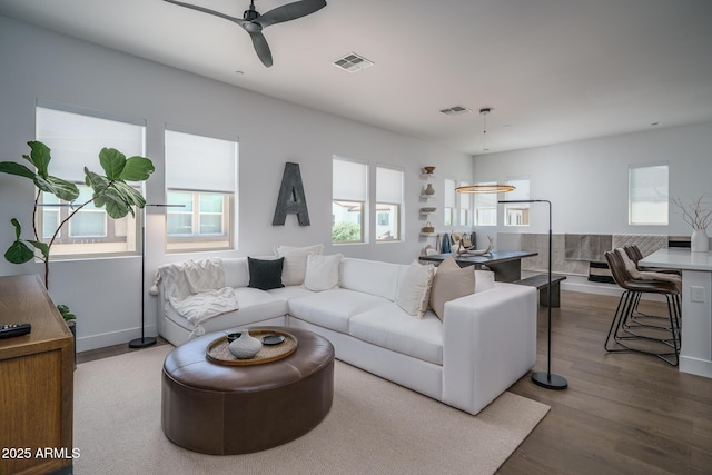 living area featuring visible vents, baseboards, and wood finished floors