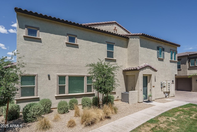 rear view of house with stucco siding and a tile roof