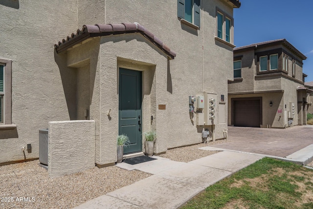 entrance to property featuring an attached garage, stucco siding, and cooling unit