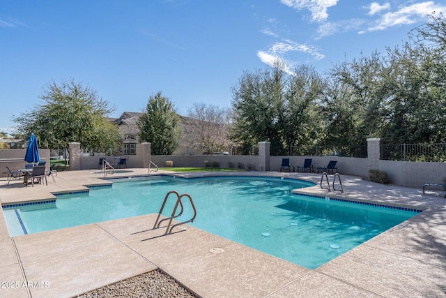 community pool with a patio, a hot tub, and fence