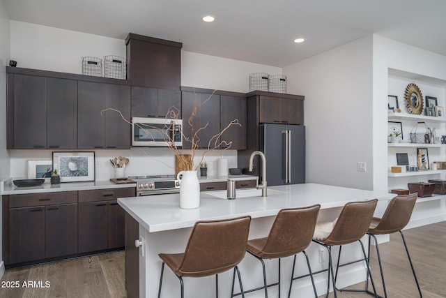 kitchen with a sink, appliances with stainless steel finishes, light wood-style floors, and a breakfast bar