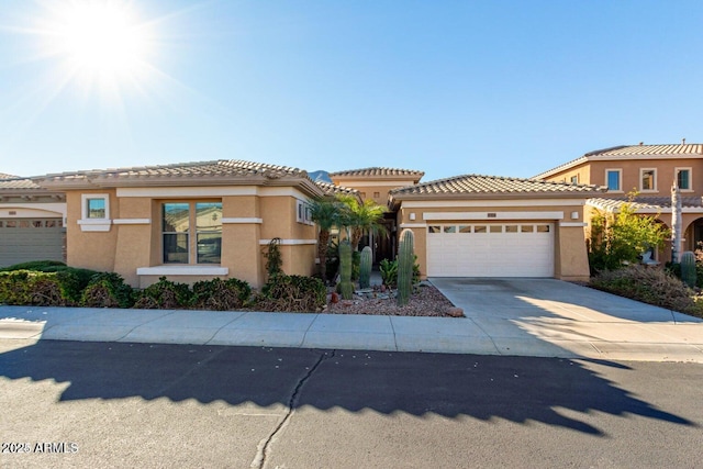 view of front of house with stucco siding, a garage, concrete driveway, and a tile roof