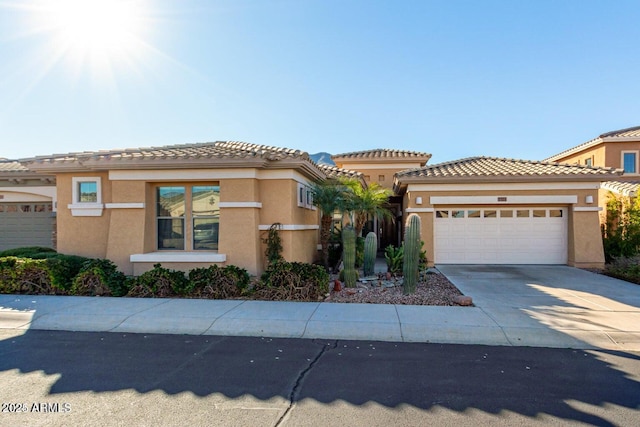 view of front facade with a tiled roof, stucco siding, driveway, and an attached garage