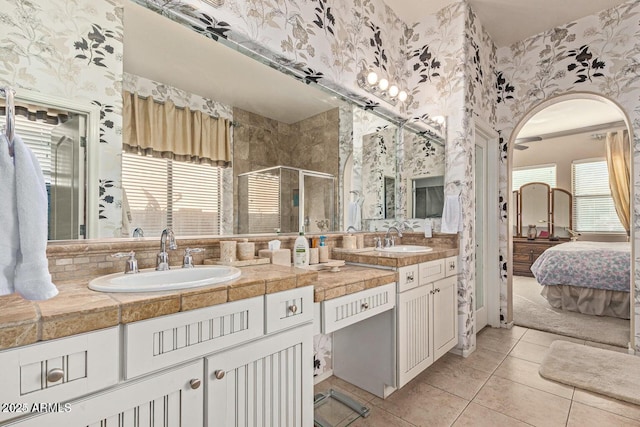 ensuite bathroom with wallpapered walls, a shower stall, and a sink