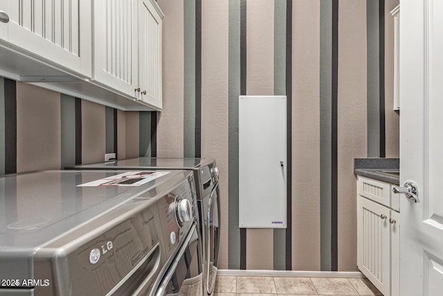 laundry room with tile patterned floors, cabinet space, and washer and clothes dryer