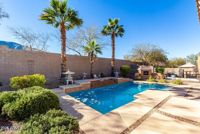 view of swimming pool featuring a patio area, an outdoor fireplace, a fenced backyard, and a fenced in pool