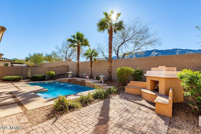 view of pool with a patio area, a mountain view, and a fenced backyard