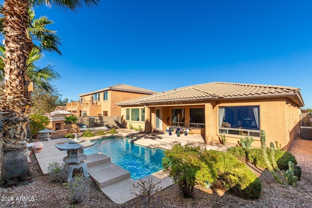 rear view of house with stucco siding, a tile roof, a patio, fence, and a fenced in pool