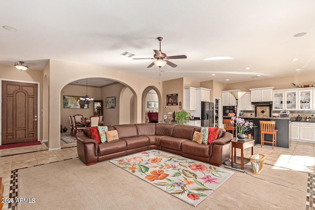 living area with light tile patterned floors, visible vents, recessed lighting, arched walkways, and ceiling fan with notable chandelier