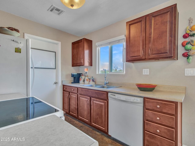 kitchen featuring white appliances, visible vents, light countertops, and a sink