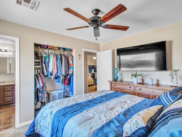 carpeted bedroom with baseboards, visible vents, ceiling fan, ensuite bathroom, and a closet