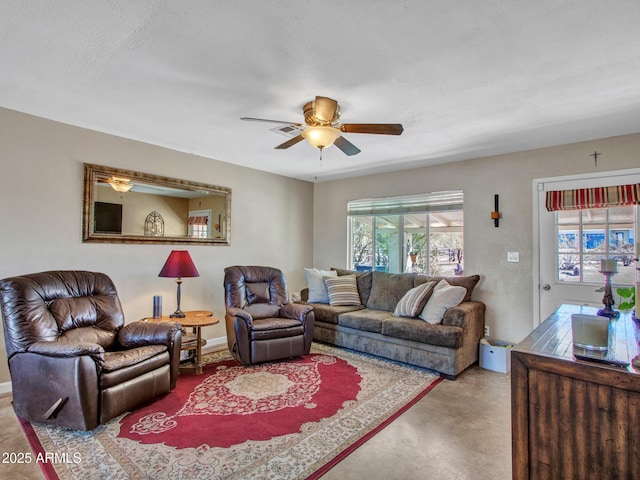 living room featuring finished concrete floors, baseboards, and a ceiling fan