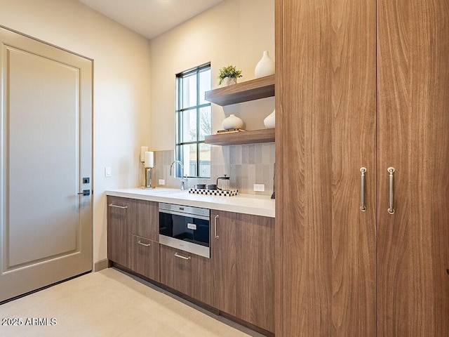 kitchen featuring open shelves, light countertops, backsplash, modern cabinets, and oven