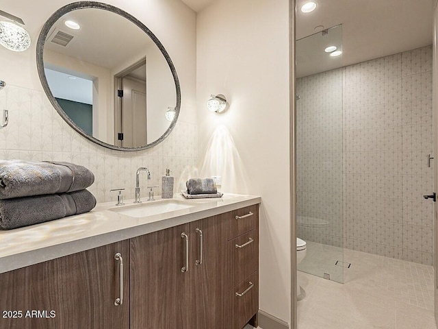 full bath with toilet, vanity, visible vents, tiled shower, and tasteful backsplash