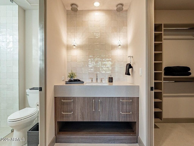 full bathroom with tile patterned flooring, toilet, vanity, tile walls, and a walk in closet