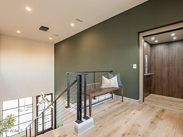 corridor with recessed lighting, visible vents, an upstairs landing, wood finished floors, and baseboards