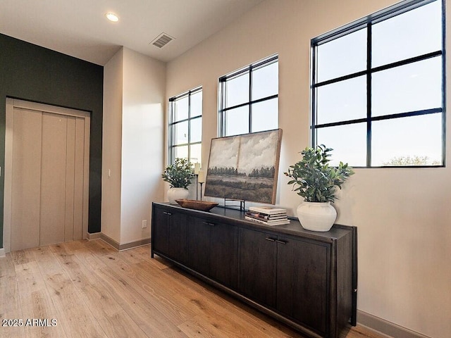 office space with light wood-style floors, plenty of natural light, visible vents, and baseboards