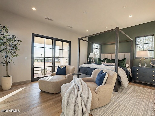 bedroom with access to outside, multiple windows, wood finished floors, and recessed lighting