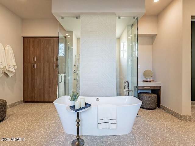 full bath featuring a freestanding bath, plenty of natural light, a shower stall, and baseboards