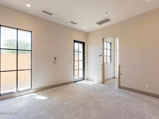 spare room featuring concrete flooring, visible vents, and baseboards