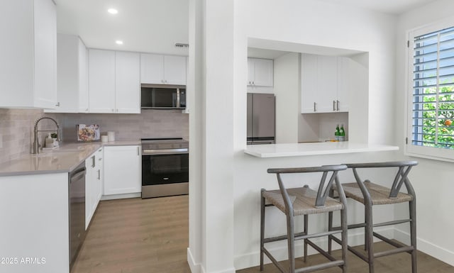 4201 E Camelback Rd Unit 70, Phoenix, AZ 85018 - kitchen featuring stainless steel appliances, a sink, tasteful backsplash, a kitchen bar, and recessed lighting