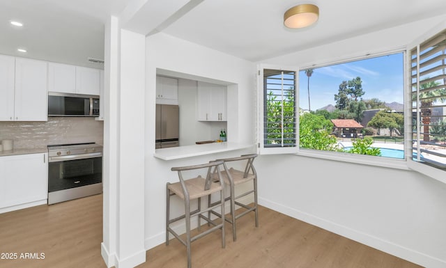 4201 E Camelback Rd Unit 70, Phoenix, AZ 85018 - kitchen featuring stainless steel appliances, baseboards, light wood-style floors, decorative backsplash, and recessed lighting