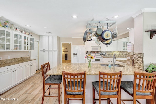 kitchen featuring a sink, backsplash, a peninsula, white appliances, and white cabinets