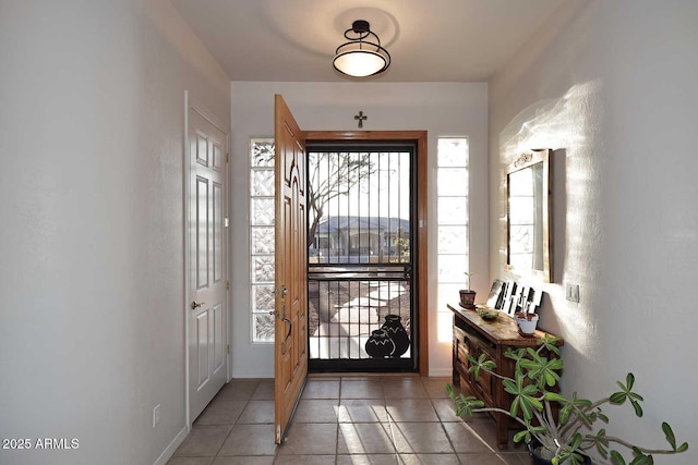 doorway featuring light tile patterned floors and baseboards