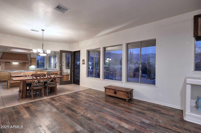 dining area with a textured ceiling, visible vents, a chandelier, and dark wood-style flooring