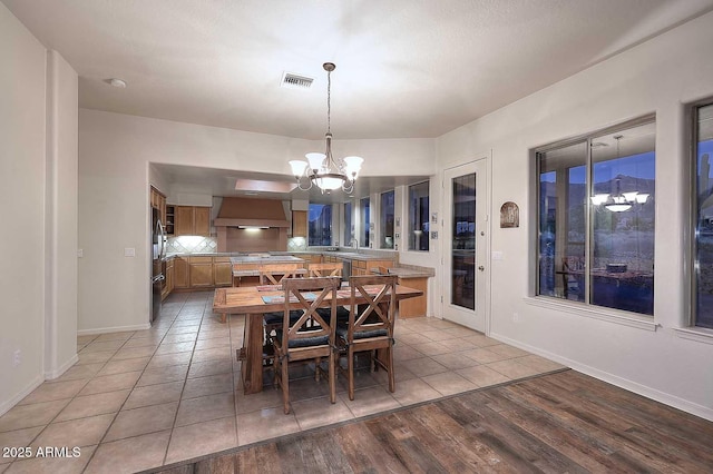 dining area featuring a chandelier, light wood-type flooring, visible vents, and baseboards