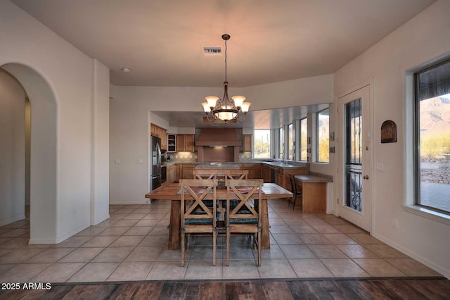 dining room featuring a chandelier, light tile patterned flooring, arched walkways, and visible vents