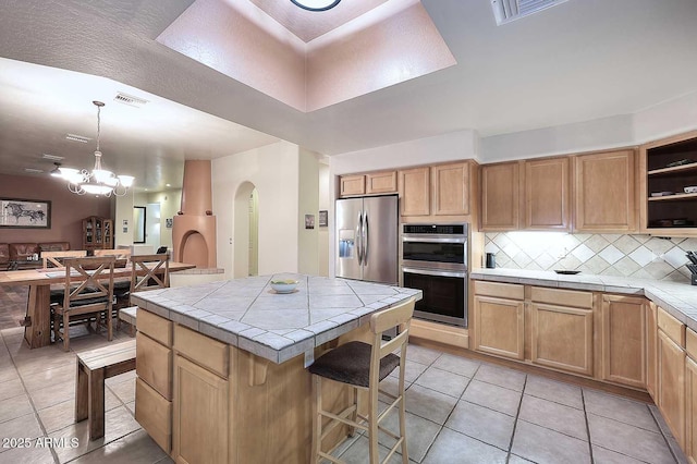 kitchen featuring tile countertops, open shelves, stainless steel appliances, backsplash, and a kitchen island