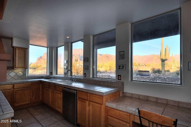 kitchen with tile countertops, brown cabinetry, a sink, and a mountain view